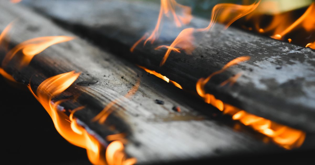 Vivid flames engulf wooden planks in an outdoor fire setting, showcasing warmth and energy.